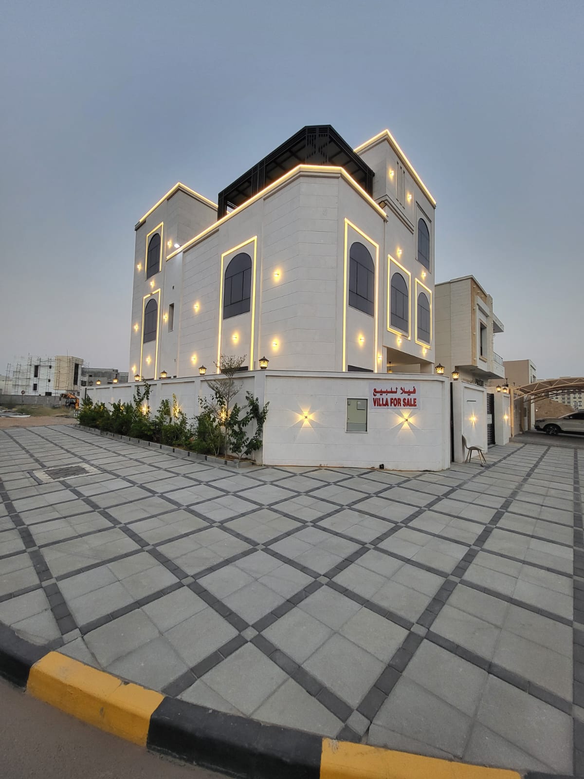 Corner Villa | Elegant two-facade stone villa with a double-sided stone boundary wall. Includes 7 master bedrooms — six spacious and one smaller room. Features a majlis, a family hall, and central duct air conditioning. A maid’s room, large main kitchen, and two pantry kitchens are also provided. The roof balcony features a stylish canopy (pergola). Equipped with German-made kitchens and cabinets, hidden-structure windows with double glazing for superior sound and heat insulation. Additional features include an underground water tank, solar water heater, and dedicated laundry area. Land area: 3,014 sq.ft. Building area: 4,449 sq.ft.